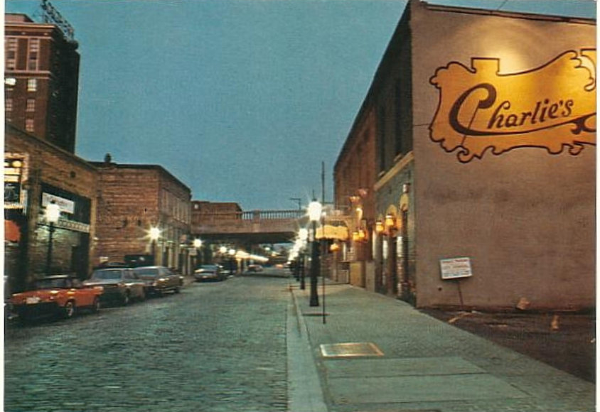 Morris Avenue during 1980s-2000s in early evening, showing buildings, cobblestone roads, and cars parked on street