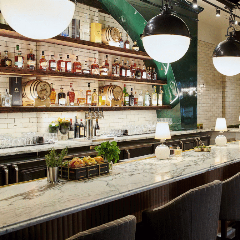 Armour House, Morris Avenue, marble bar with chairs and drinks in shelves behind bar. Large round lights hang from ceiling