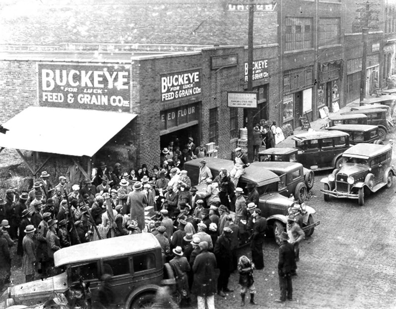 Morris Avenue in 1930s-1950s, crowd of people and cars outside Buckeye Feed and Grain Co.