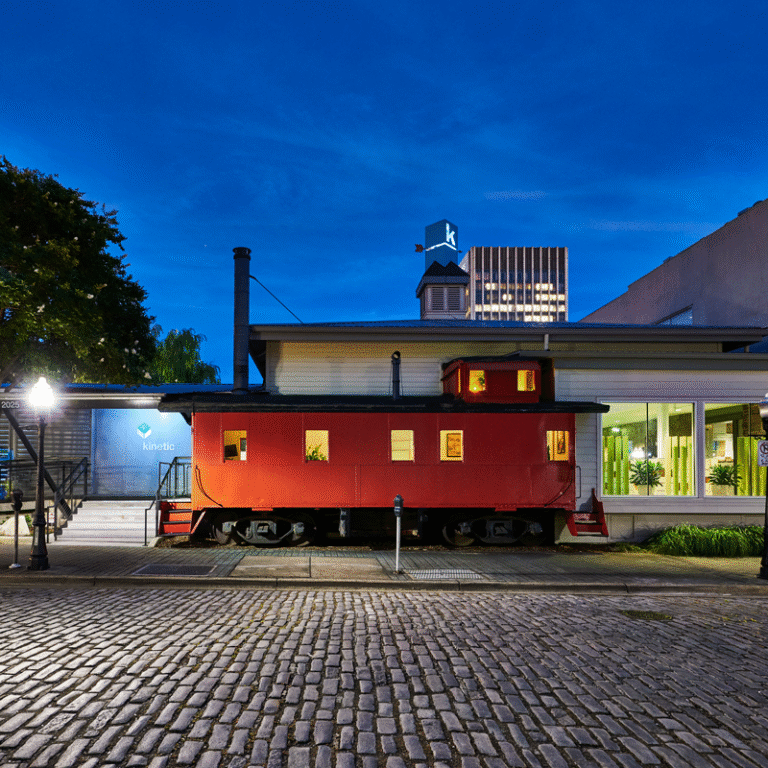 Kinetic Communications, Morris Avenue, red caboose building by cobblestone street in evening