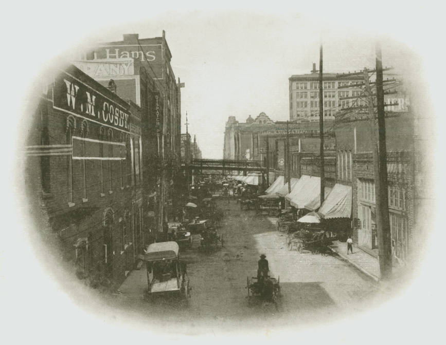 Morris Avenue in 1900s-1920s, buildings lining a busy street filled with carriages and automobiles